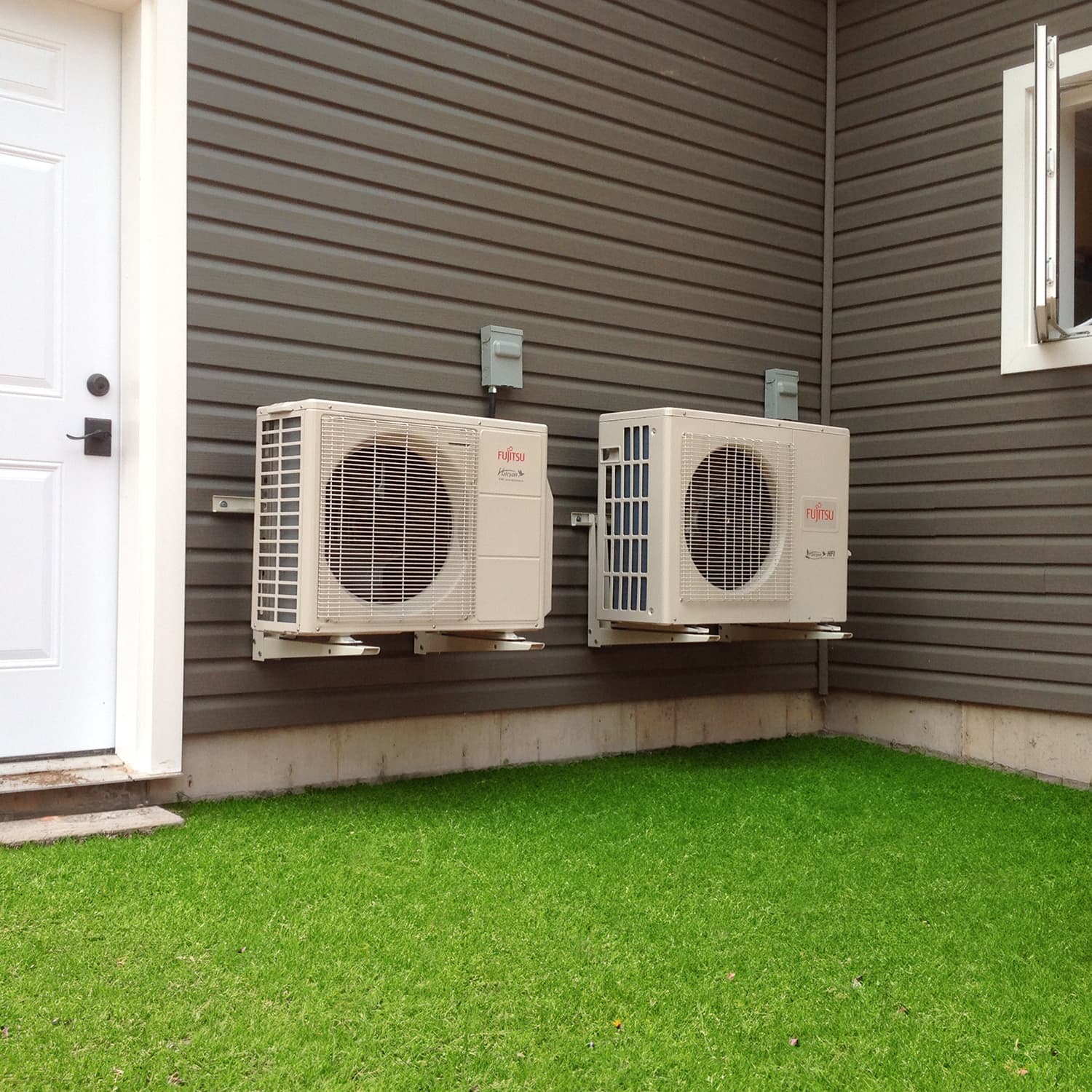 Two heat pump units mounted on the exterior of a house